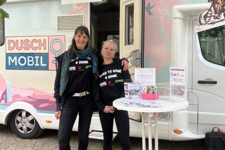 Zwei Crewmitglieder stehen vor dem Duschmobil für Frauen